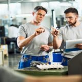 Industrial workers cooperating while doing quality control of manufactured products in a factory.